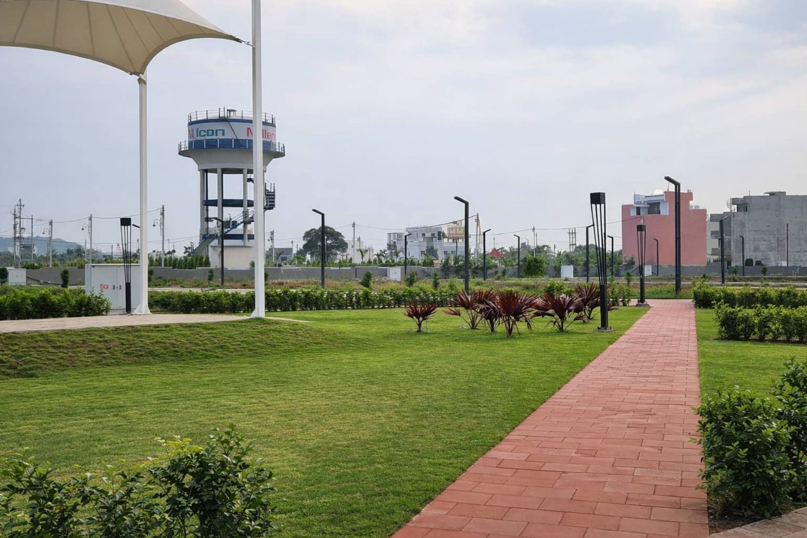 Landscaped lawn with a red-paved walkway, shade canopy and water tank